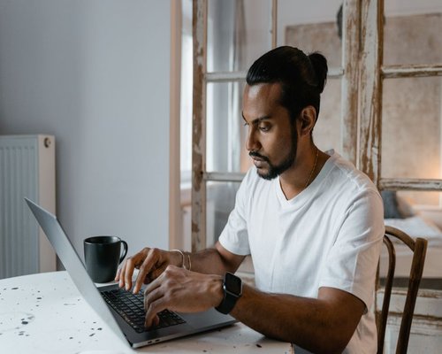 A person typing on a laptop with good posture in a bright room